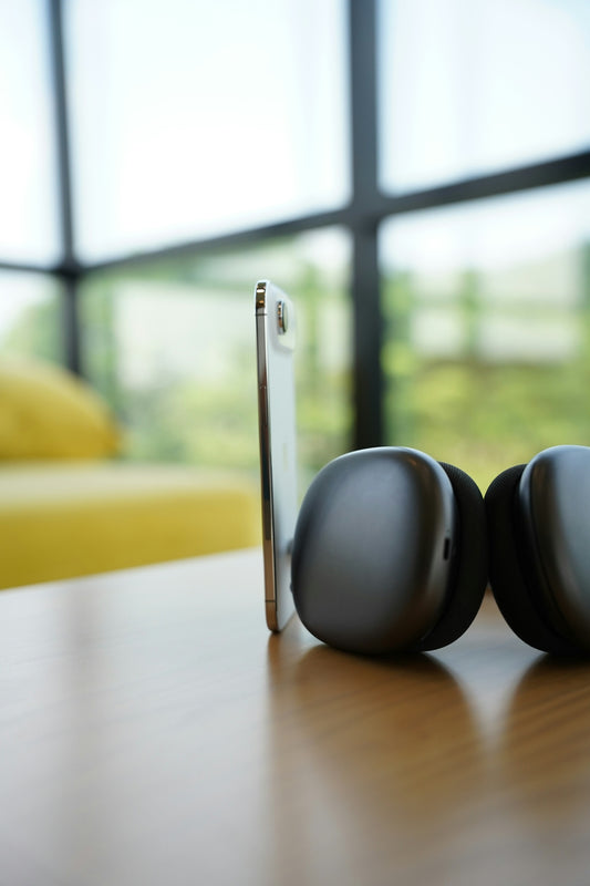 Smartphone and headphones resting on a wooden table.