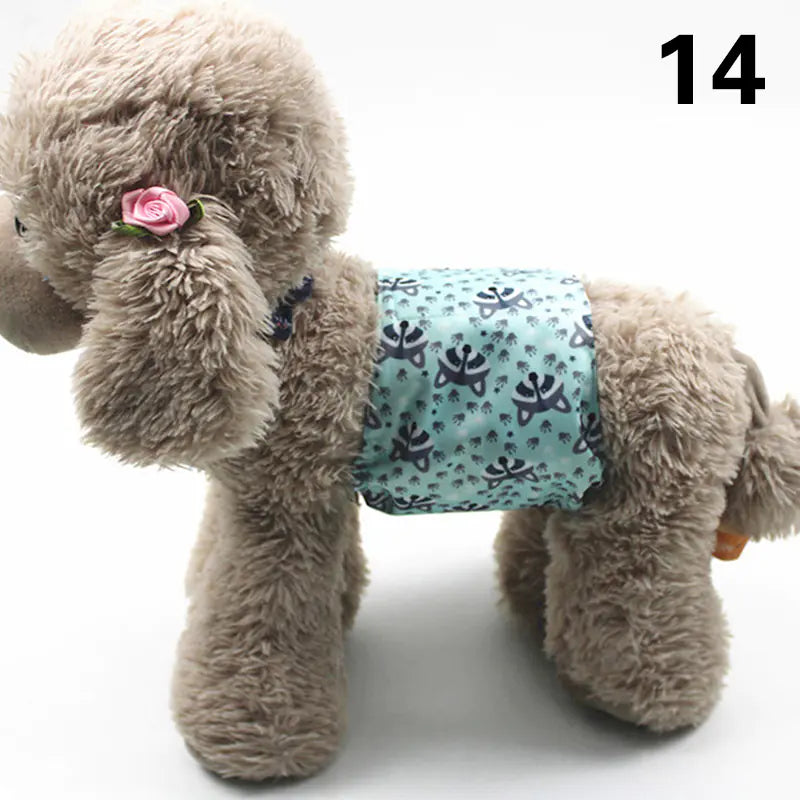 Fluffy gray dog plush toy with a pink flower accessory and a patterned turquoise diaper or pad on its body, positioned on a white background.