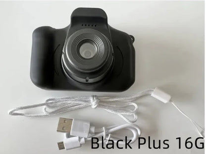 Compact kids camera with large lens for clear photos. Black camera body with USB charging cable and lanyard strap.