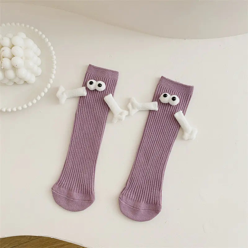 Cute solid color kids' mid-calf socks with googly eyes, displayed on a white background with decorative elements.